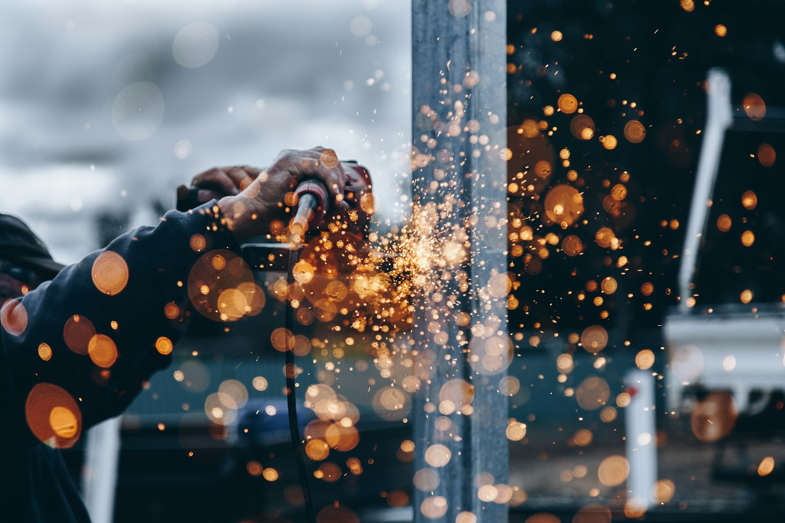A grinder dressing a steel section and throwing sparks